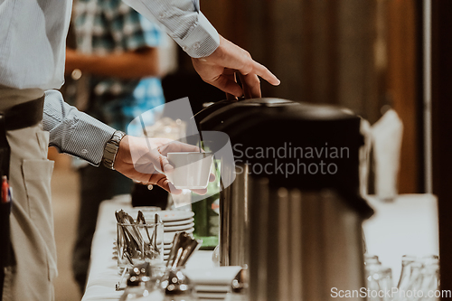 Image of The waiter preparing coffee for hotel guests. Close up photo of service in modern hotels