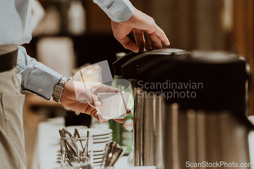 Image of The waiter preparing coffee for hotel guests. Close up photo of service in modern hotels