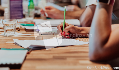 Image of Closeup shot of business people hands using pen while taking notes on education training during business seminar at modern conference room