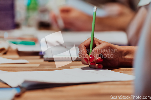 Image of Closeup shot of business people hands using pen while taking notes on education training during business seminar at modern conference room