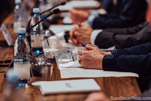 Image of Closeup shot of business people hands using pen while taking notes on education training during business seminar at modern conference room