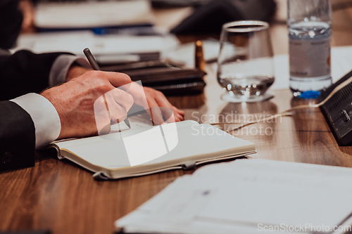 Image of Closeup shot of business people hands using pen while taking notes on education training during business seminar at modern conference room