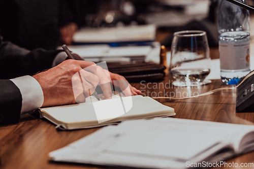 Image of Closeup shot of business people hands using pen while taking notes on education training during business seminar at modern conference room