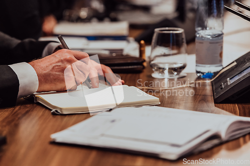 Image of Closeup shot of business people hands using pen while taking notes on education training during business seminar at modern conference room