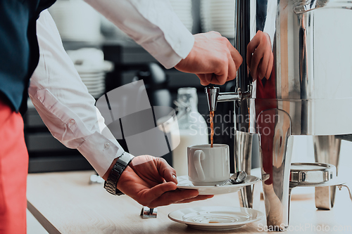 Image of The waiter preparing coffee for hotel guests. Close up photo of service in modern hotels