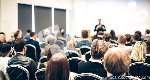 Image of Speaker giving a talk in conference hall at business event. Rear view of unrecognizable people in audience at the conference hall. Business and entrepreneurship concept.