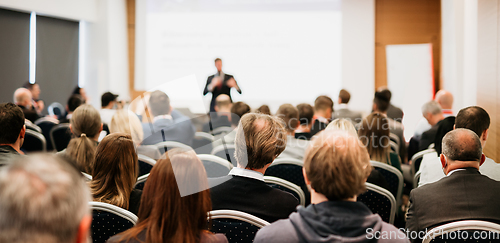 Image of Speaker giving a talk in conference hall at business event. Rear view of unrecognizable people in audience at the conference hall. Business and entrepreneurship concept.