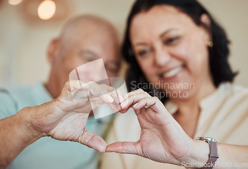 Image of Hands, heart and love with a senior couple in their home for health, wellness or trust during retirement. Emoji, shape or hand gesture with an elderly man and woman closeup in their house together