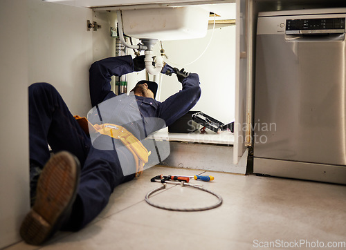 Image of Kitchen, maintenance and renovation with a plumber on the floor of a home to fix a leak, issue or problem. Plumbing, repair and tools with a handyman or contractor working on a pipeline in a house