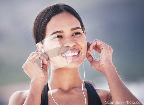 Image of Fitness, smile and woman with music earphones outdoor for running, training and sports routine on blurred background. Exercise, podcast and happy female runner with radio, track and audio motivation