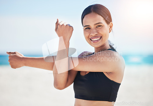 Image of Beach, portrait and happy woman stretching arm in nature for fitness, running or exercise, body or wellness. Face, smile and lady runner with shoulder stretch at sea for sports, training or ocean run