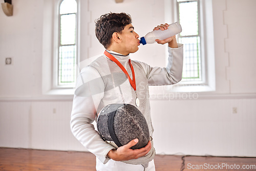 Image of Sports, fencing and man drinking water for training, fitness or workout with helmet in club. Bottle, fencer or athlete with beverage after exercise with liquid for nutrition, body health or wellness