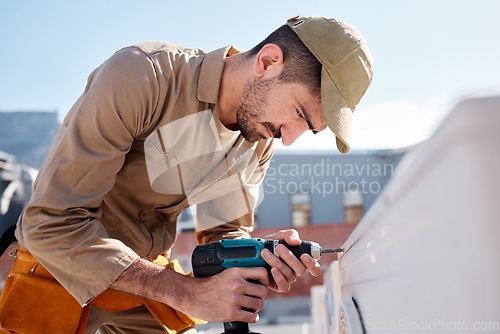 Image of Technician man, drill and outdoor with air conditioner maintenance, roof or building in metro cbd for construction. AC repair, hvac tech and tools for engineer, service and aircon industry on rooftop