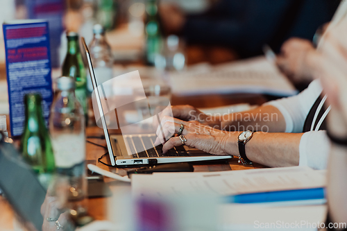 Image of Close up photo of an elderly woman typing on a laptop at a seminar