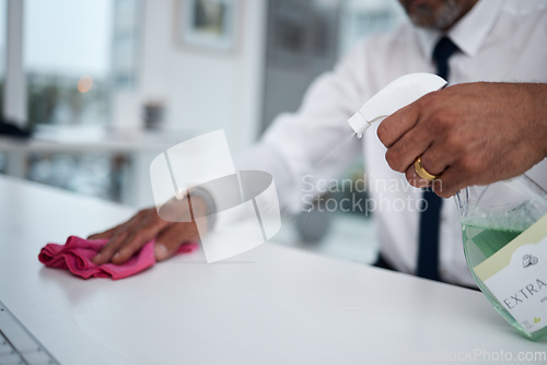 Image of Man, hands and cleaning table in office with cloth, spray bottle and hygiene for safety of virus. Closeup of worker wipe dirty desk, surface and sanitation of dust, disinfection and risk of bacteria