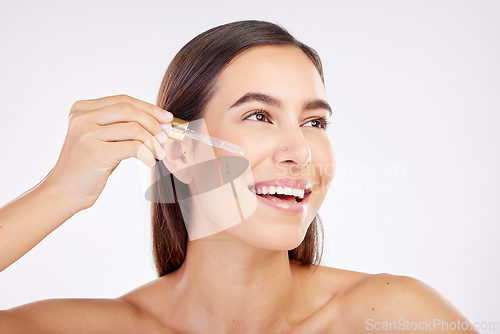 Image of Facial skincare, smile and woman with a serum, cosmetics or happiness on a white studio background. Female person, model or girl with essential oil, retinol product or dermatology with natural beauty