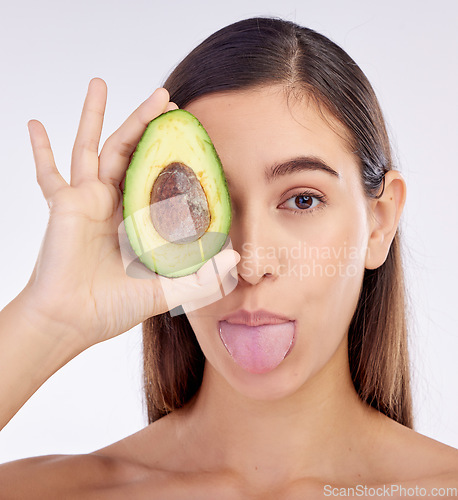 Image of Face, skincare and woman with avocado, tongue out and isolated on a white background in studio. Portrait, beauty and natural model with fruit food for nutrition, healthy diet or omega 3 for wellness