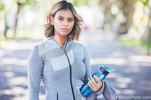 Image of Runner woman, bottle and portrait in park, ready and exercise with fitness training in nature. Indian girl, commitment and pride for wellness, health or outdoor workout for body, self care or goals