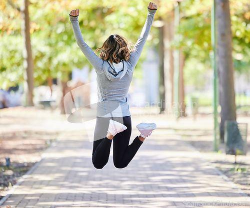 Image of Fitness, jump and a woman outdoor for success at a park to celebrate win or achievement. Back of young female person on a road in nature excited about workout, running or training goals or freedom