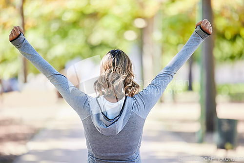 Image of Fitness, exercise and a woman outdoor with hands raised at a park for celebration, win and success. Back of young female person on a road in nature excited about workout, running or training goals