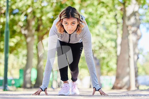 Image of Run, exercise and a woman in start position outdoor at a park with commitment and focus on wellness. Young female person on a road in nature ready for workout, running or training for marathon