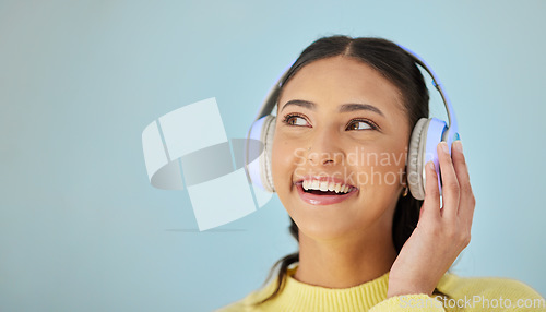 Image of Woman with smile, headphones and mockup in studio thinking with technology on mobile app and streaming radio site. Podcast, music media subscription and happy girl with sound on blue background space