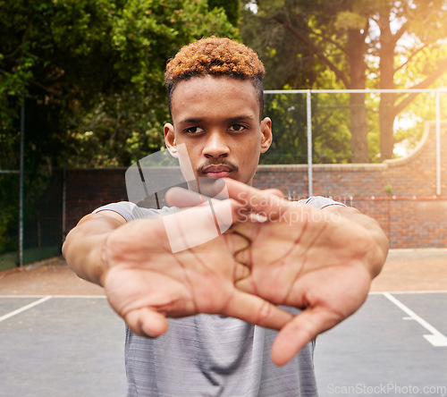 Image of Sports, basketball and man stretching on court for competition, training or fitness games. Face of serious male athlete, player and warm up arms for workout, thinking of performance action or contest