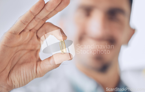 Image of Man, hand of doctor and pill, pharmaceutical drugs and treatment of illness at hospital with blurred background. Healthcare, medicine and medical professional with gold capsule to help with health.