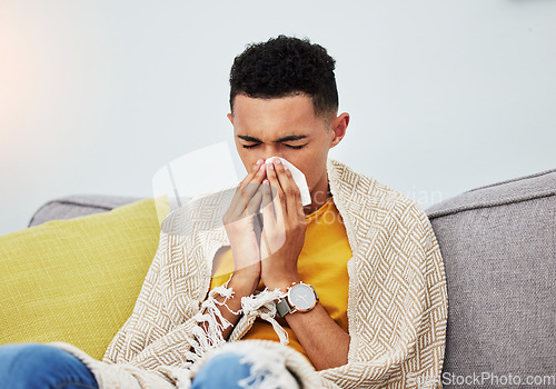 Image of Sick, couch and man blowing nose with flu, cold and sinus fever in a home living room with a blanket on a sofa. Healthcare, sneeze and young person with difficult symptoms or medical problem in house