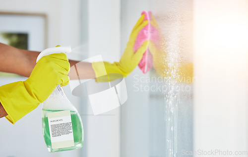 Image of Window, spray and hands cleaning in a home for hygiene, germ protection and maintenance with a chemical in a house. Bacteria, glass and housekeeper or cleaner working on a wood desk with gloves