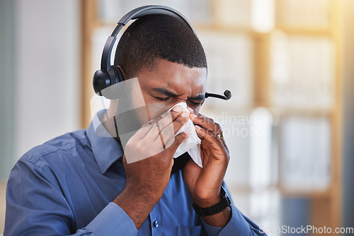 Image of Sick, black man and blowing nose in call center office for flu, allergies, and health risk in telemarketing agency. Face of salesman, CRM agent and tissue for virus, bacteria and sneeze for allergy