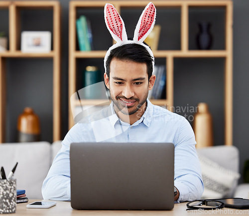 Image of Laptop, bunny ears and business man in office with decoration for celebration, event and Easter party. Corporate, happy and Asian male person on computer at desk with rabbit headband for holiday