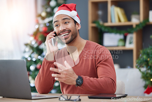 Image of Phone call, christmas hat and man in the office with a laptop on a cellphone for communication. Happy, smile and young male creative designer with xmas decorations on mobile conversation in workplace