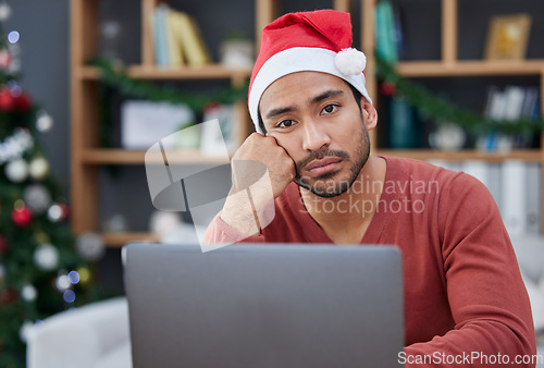 Image of Bored, christmas hat and portrait of a tired man in the office with a laptop working on a project. Burnout, exhausted and young male creative designer with xmas decorations in the modern workplace.