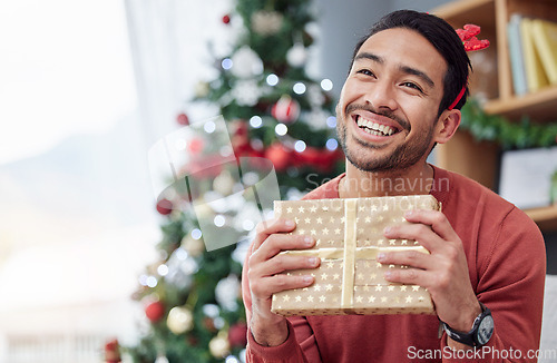 Image of Christmas, surprise and asian man with gift in his home happy, excited and having fun celebrating holiday. Hand holding, box and Japanese male with present in a living room at December party or event