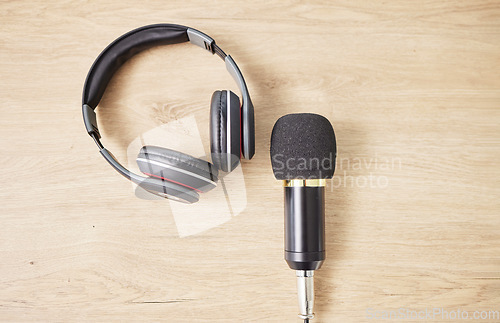 Image of Above, microphone and headphones on a table for a podcast, radio or broadcast. Music, desk or musical gear, equipment or a mic for live streaming, musician recording or technology in an office