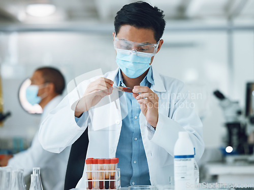 Image of Exam, blood sample and scientist doing research with face mask in a laboratory for medical analysis in a lab. Science, medicine and professional Asian man working on test of DNA in a vial tube