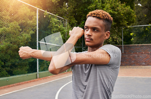 Image of Man, basketball and stretching arms for sports flexibility, action and mobility. Workout, fitness and strong player with focus on court to prepare for training, exercise and thinking of competition