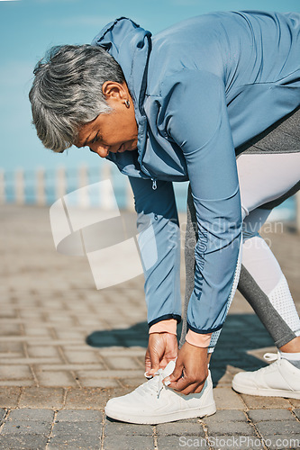 Image of Fitness, beach and senior woman tie shoes ready for wellness, workout or training in the morning for health. Rest, sport and elderly person prepare for outdoor exercise by typing sneakers or running