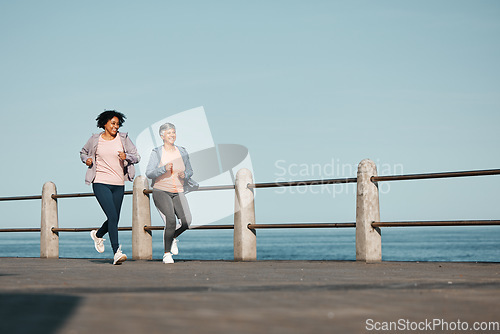 Image of Senior, fitness and women friends at the beach for running, bond and morning cardio in nature together. Ocean, workout and elderly female runners happy, talking and enjoy fresh air, run and training