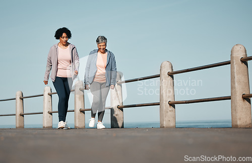 Image of Fitness, walking and senior women by ocean for healthy lifestyle, wellness and cardio on promenade. Sports, friends and female people in conversation on boardwalk for exercise, training and workout