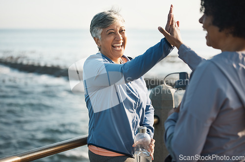 Image of High five, fitness and senior women friends at beach with exercise, celebration and excited in nature. Sport, people and elderly females with hands in support of wellness, training or success at sea