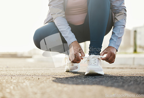 Image of Fitness, runner and woman tie shoes outdoor in the road for running workout in the city. Sports, health and closeup of female athlete tying her laces for cardio exercise for race or marathon training