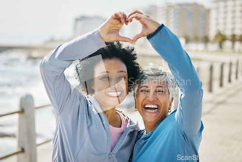 Image of Heart, hands and fitness with portrait of friends at beach for health, support and love. Motivation, happy and wellness with mature women and sign in nature for exercise, workout and emoji icon