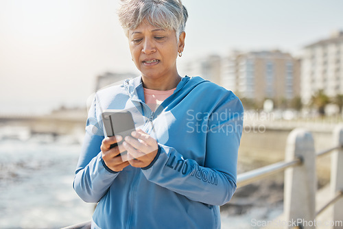 Image of News, phone and fitness with old woman at beach for running, workout and results. Network, communication and contact with female runner training in nature for technology, sports and mobile app