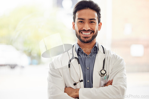 Image of Portrait, smile and asian man doctor with arms crossed in hospital with stethoscope for consulting on blurred background. Happy, face and male healthcare expert proud of clinic, service or help