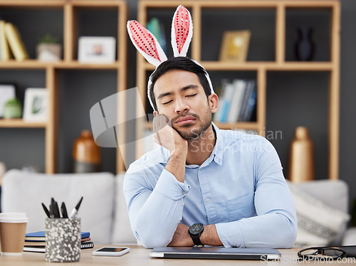 Image of Tired, sleeping and a man for easter in an office with bunny ears for celebration or bored of a party. Stress, rabbit and a young Asian businessman with fatigue at a work desk with a problem