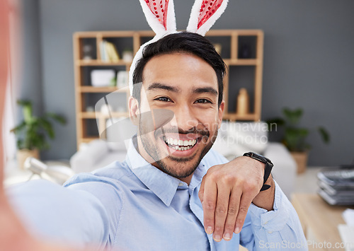 Image of Bunny ears, holiday and remote work selfie with a man and social media with creative job. Celebration, happy face and male person from Spain feeling silly and goofy with comedy easter hat at home