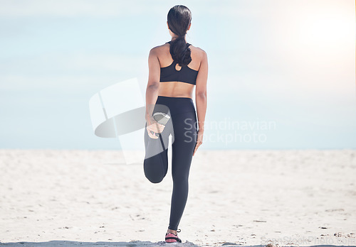 Image of Fitness, woman back and stretching leg at beach for running, workout and body, exercise or wellness routine. Foot, stretch and behind female runner at sea for training, sports or physical performance