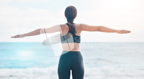 Image of Fitness, freedom and woman back at the beach stretching arms after running or cardio routine in nature. Exercise, rear view and female at the ocean with body stretch for training success or milestone